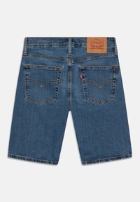 Modré džíny šortky se rovný střih, obsahující dvě zadní kapsy, žluté prošívání a koženou nášivku s logem na pase.