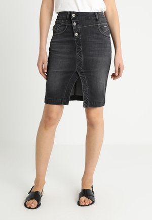Zwarte denimrok met een rechte snit, sluiting met vijf knopen en een vooraan een split. Heeft zichtbare naden en een klassieke tailleband.