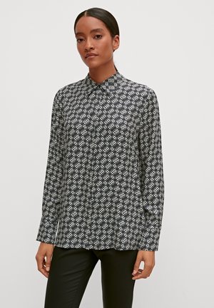 Black and white patterned long-sleeve shirt with a collar, featuring a geometric design. The fabric appears smooth and lightweight.