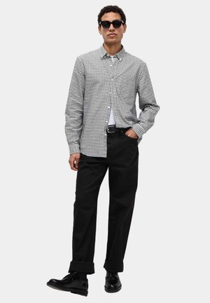 Schwarz-weiß kariertes Hemd mit Knöpfen, lange Ärmel, aus Baumwollmaterial. Kombiniert mit hoch taillierten schwarzen Hosen und schwarzen Schuhen.