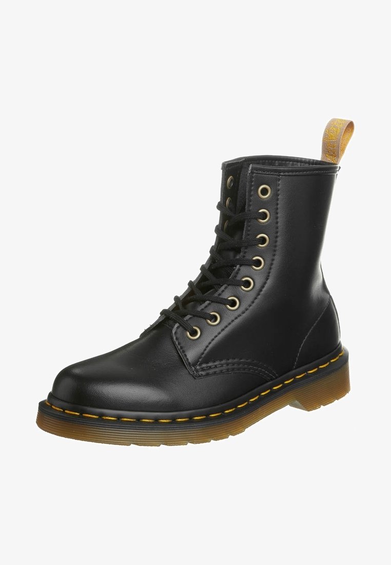 Botín de cuero negro con cordones, punta redonda, costuras amarillas y suela de goma texturizada. Presenta ojetes metálicos y una tira de sujeción.