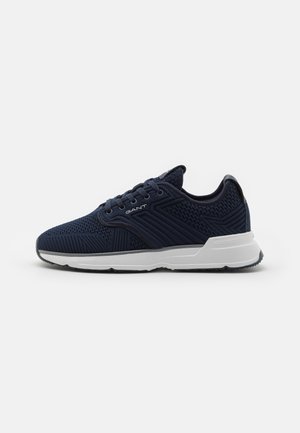 Navy blue athletic shoe with a textured mesh upper, lace-up design, contrasting white sole, and subtle logo detail on the side.
