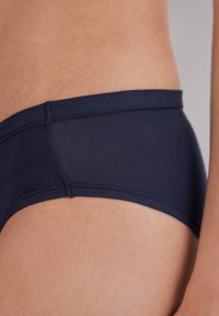 Donker marineblauwe hipsteronderbroek gemaakt van rekbare stof. Heeft een gladde textuur en een zachte tailleband met minimale naden voor comfort.