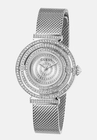 Srebrny zegarek z siatkowym paskiem, okrągła tarcza z koncentrycznymi pierścieniami kryształów oraz prosta tarcza analogowa z wskazówkami godzinową i minutową.