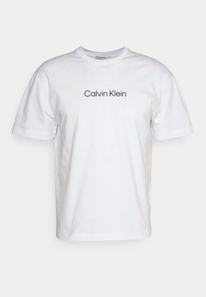 White cotton t-shirt featuring a crew neck and short sleeves, with "Calvin Klein" printed in black on the front center.