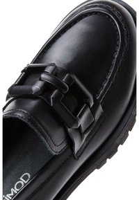 Schwarze Lederloafer mit einem breiten Riemen und strukturiertem Schnallen-Detail, abgerundeter Zehenform und kontrastierender, profiliertem Gummisohle.