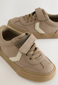 Tan ruskinds sneakers med en tekstureret overflade, udstyret med brune snørebånd, en velcrolukning og et kontrastfyldt hvidt design.