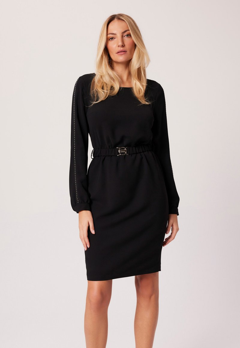 Czarna sukienka z długim rękawem i ściśniętą talią, z okrągłym dekoltem oraz dekoracyjnym przeszyciem na rękawach. Gładka struktura materiału.