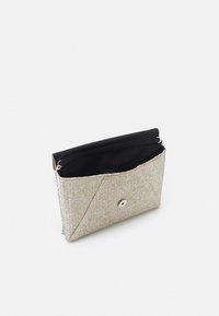 Clutch de tejido beige con diseño angular, detalles en plata y forro de tela negra. Cuenta con una correa de cadena y cierre a presión.