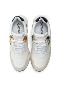 Sneaker bianche con accenti testurizzati, dotate di una tomaia in pelle liscia, tallone nero a contrasto e accessori dorati decorativi sul lato.
