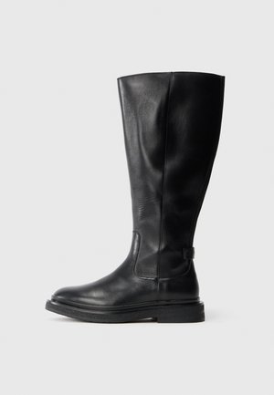 Botte noire en cuir, montant jusqu'au genou, avec un bout rond, un-dessus légèrement texturé et une semelle en caoutchouc. Équipée d'un panneau latéral pour un enfilage facile.
