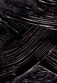 Close-up of smooth, shiny black paint with thick, textured brush strokes forming diagonal lines and ridges.