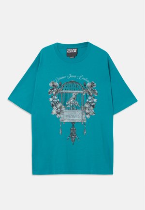 Türkises, lässig geschnittenes T-Shirt mit einem detaillierten silbernen Vogelkäfig, floralen Motiven und dem Schriftzug "Versace Jeans Couture" auf der Vorderseite.