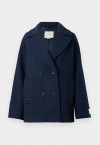 Cappotto doppiopetto navy in misto lana, con rever a punta, grandi tasche frontali e bottoni neri. Texture liscia con accenti minimi.