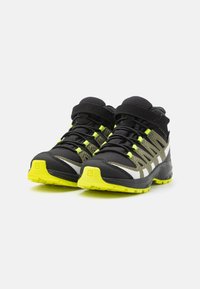 Czarne i szare buty trekkingowe z żółtymi akcentami; siateczkowy i syntetyczny materiał; wysokie cholewki; teksturowana powierzchnia; wytrzymała podeszwa z bieżnikiem.