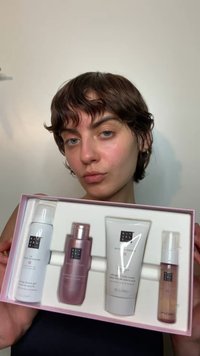 Cztery produkty do pielęgnacji skóry w różowym pudełku: biały żel pod prysznic, różowy olejek pod prysznic, biały bita krem do ciała oraz przezroczyste serum do twarzy.