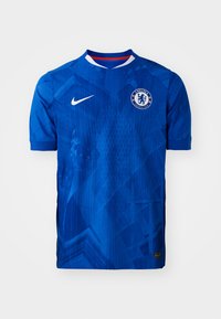 Niebieska koszulka piłkarska Chelsea FC, krótki rękaw, z geometrycznym wzorem, logo Nike i herb drużyny; wykonana z lekkiego materiału syntetycznego.