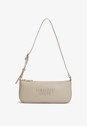 Beige Tommy Jeans shoulder bag with slim rectangular shape, embossed logo, adjustable strap, and zipper closure at the top.