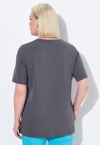 Grijze korte mouwen t-shirt met een ronde halslijn, een gladde textuur en een relaxte pasvorm, gedragen met blauwe broek. Eenvoudig ontwerp, geen patronen of accenten.