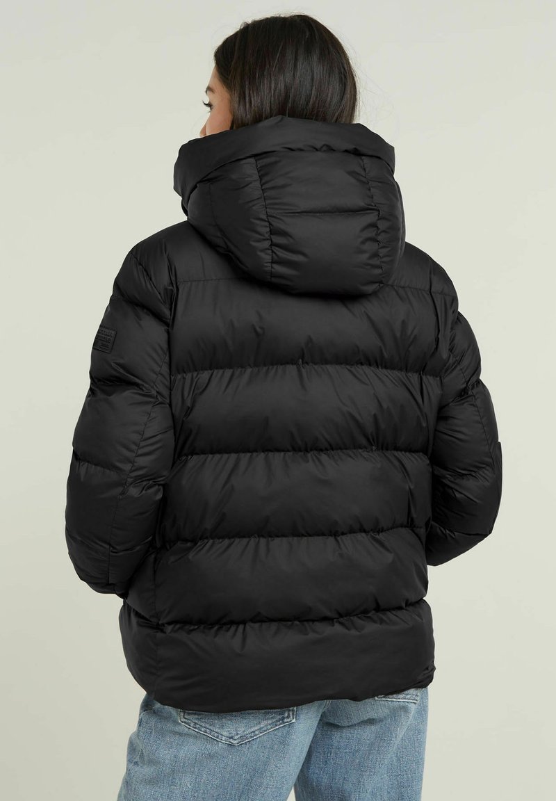 Schwarze Pufferjacke mit Kapuze, ausgestattet mit einem gesteppten Design, dicker Polsterung und hohem Kragen. Strukturierte Oberfläche und elastische Bündchen.