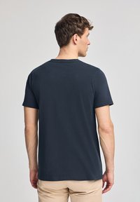 Granatowa koszulka z krótkim rękawem wykonana z bawełny, z okrągłym dekoltem i prostym krojem, pokazana z tyłu o gładkiej fakturze.