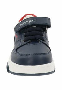 Zapatilla de cuero azul oscuro con suela blanca, que presenta una correa de Velcro, cordones negros y detalles rojos en la lengüeta y el talón.