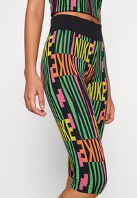 Leggings capri Nike con un motivo multicolore a righe verticali nei colori verde, giallo, rosa e nero. Tessuto morbido e elastico.