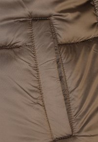 Brązowa kurtka puchowa z gładką teksturą, geometrycznym przeszyciem i widoczną prostokątną kieszenią na przedniej lewej stronie.