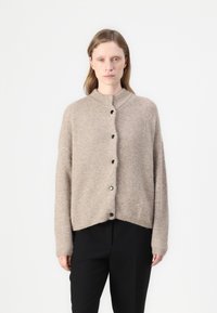 Beige kötött kardigán kerek gallérral, nagy fekete gombokkal, széles ujjal és enyhén rövidített szegéllyel rendelkezik. Puha tapintású.