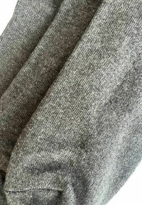 Grau gestrickter Stoff, der eine strukturierte Oberfläche mit einer Mischung aus hellen und dunklen Fasern zeigt, leicht dehnbar und mit einem weichen Finish.