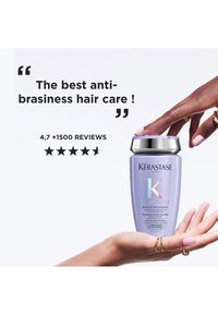 Hand mit Ringen hält eine Flasche Kérastase Blond Absolu Shampoo mit Lavendel, während eine andere Hand den Verschluss berührt, mit einer 4,7-Sterne-Bewertung und einer Bewertungsaussage.