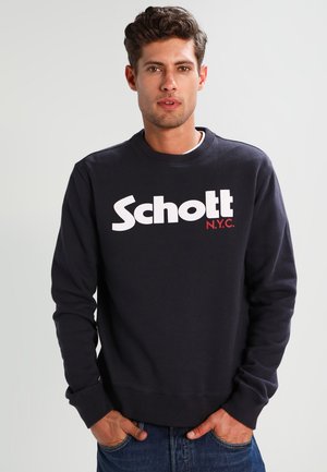 Felpa in cotone blu navy con collo rotondo, caratterizzata da un audace logo bianco "Schott" e un accento rosso "N.Y.C.". Texture liscia, vestibilità comoda.