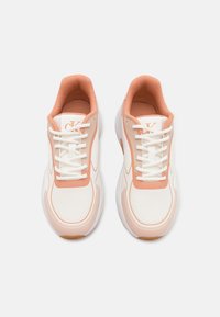 White athletic sneakers with peach accents, mesh and synthetic upper, round toe, padded collar, and textured rubber sole. Laces and logo detail included.