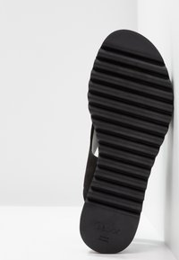 Semelle de chaussure en caoutchouc noir avec des rainures horizontales, estampillée "Gabor". Les parties supérieures sont texturées, montrant un mélange de matériaux.