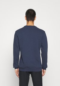 Felpa blu navy in misto cotone, con scollatura rotonda, maniche lunghe, polsini a coste e un piccolo etichetta sul retro.