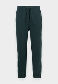 Pantalons de survêtement vert foncé avec une taille élastique, un cordon de serrage et des poignets côtelés ; présente un logo en relief subtil à l'avant.