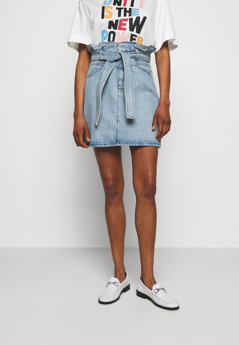 Jeanskjol med bälte i midjan, ljusblå färg, rak skärning och rå kant. Kombinerad med en vit T-shirt med lös passform och vita loafers.