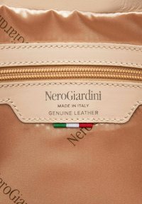 Beżowe wnętrze z prawdziwej skóry, z kieszonką na zamek błyskawiczny wyłożoną beżowym satynowym materiałem. Metka nosi napis "NeroGiardini, Made in Italy" z akcentem w kolorze włoskiej flagi.