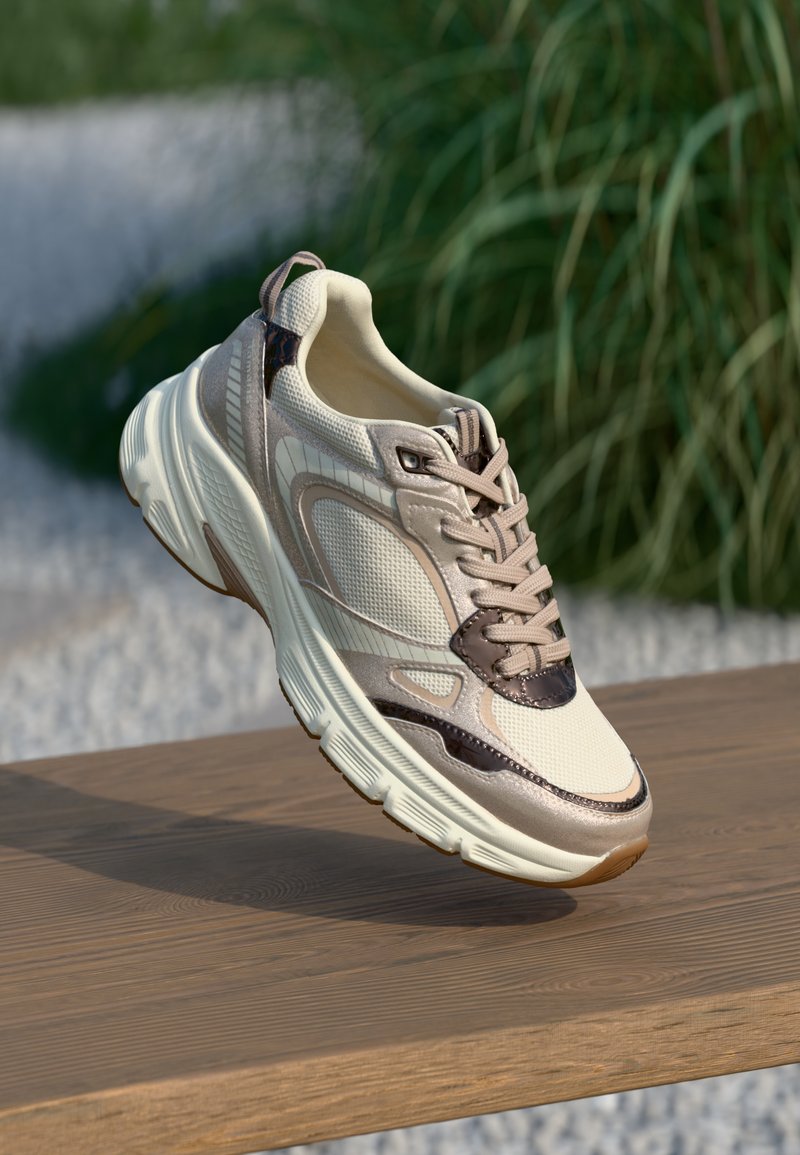 Baskets beiges en tissu avec des accents en cuir, à bout rond, avec des panneaux texturés et une semelle légère. Des lacets fins et une languette au talon sont visibles.