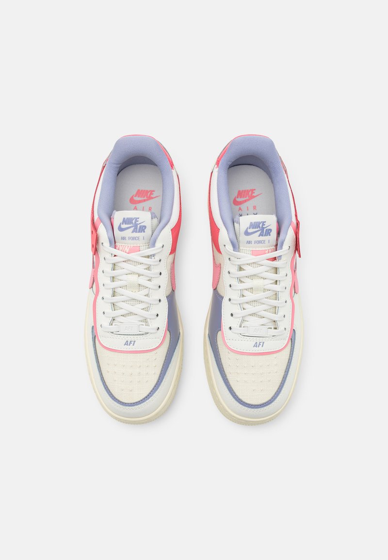 Sneakers Nike Air Force 1 w białym, jasnopurpurowym i różowym wzorze. Cechy to teksturowana cholewka oraz solidna, biała podeszwa.