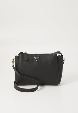 Sac bandoulière en cuir noir texturé avec ferrures dorées et logo Guess sur le devant, sur un fond clair uni.