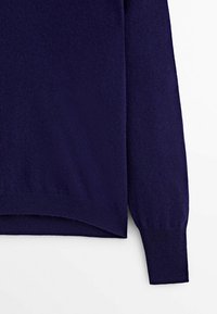 Pull en maille bleu marine à manches longues, avec des poignets côtelés et un ourlet légèrement incurvé. Fabriqué en tissu doux et texturé.