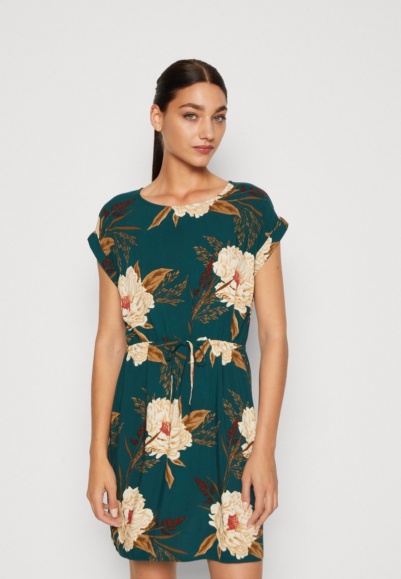 Vestido teal de manga curta com padrões florais em creme, decote redondo e uma cintura franzida com detalhe de laço.