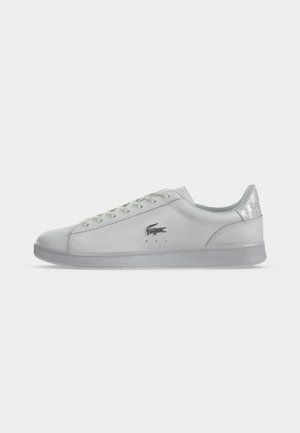 Hvid lavtop-sneaker med snørelukning foran, gummisål og lille sort krokodillelogo på siden, vist i sideprofil.