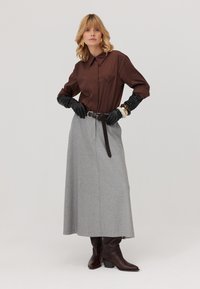 Brązowa koszula z kołnierzykiem, szara długa spódnica, czarne rękawiczki, brązowy pasek z złotymi akcentami oraz brązowe botki na obcasie, z teksturowanej tkaniny i gładkim wykończeniu.