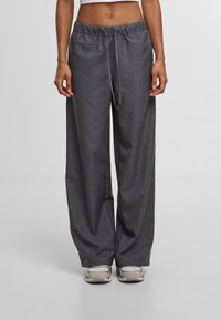 Grijze wijde broek van textuurstof met een elastische tailleband en koord. Gecombineerd met lichtgekleurde sneakers.