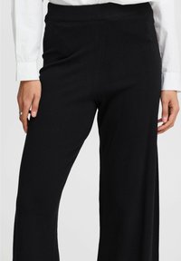 Zwarte wijde broek met een geribbelde elastische tailleband, met een gladde textuur en een minimalistisch ontwerp.