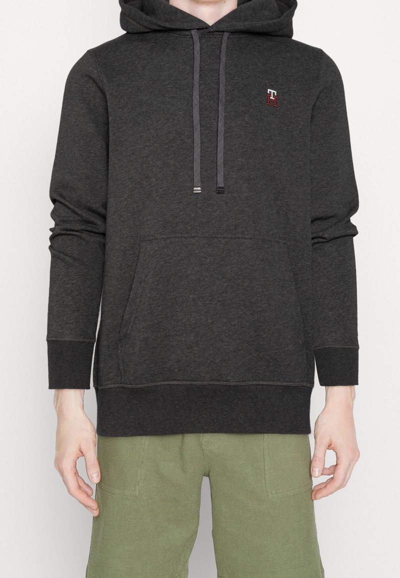 Donkere grijze hoodie met een kangoeroezak, capuchon met trekkoorden en geborduurd logo. Gemaakt van zachte stof, voorzien van geribbelde manchetten en zoom.