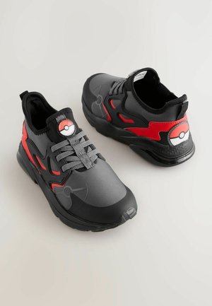 Sneaker neri e rossi realizzati in materiale sintetico, con un design a Pokéball sulla linguetta e sul lato, dotati di una suola intermedia texturizzata e lacci.