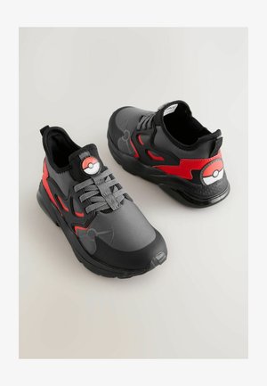 Fekete és piros sneaker, szintetikus anyagból készült, Pokéball mintával a nyelvén és az oldalán, texturált középtalppal és fűzőkkel.